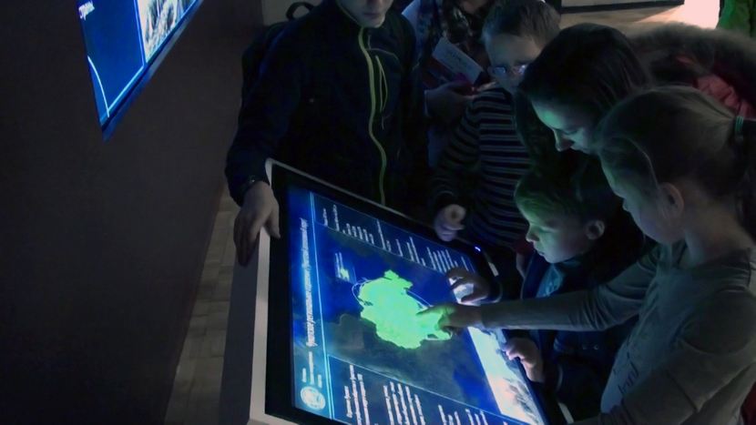 Посетители Фестиваля у сенсорного киоска, управляющего интерактивной картой.